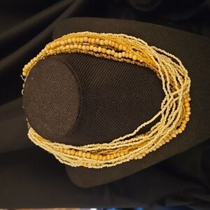Strands of cream, tan, and brass beads make-up this multiple strand Necklace